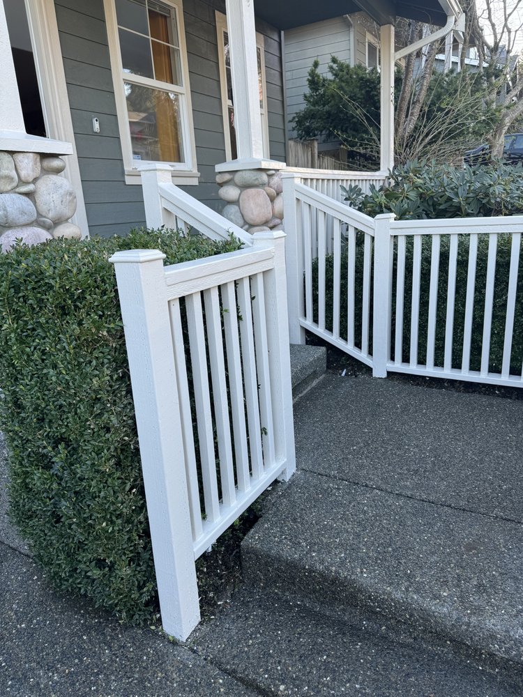Repainted white railing and gate against gray siding and stone columns after the job