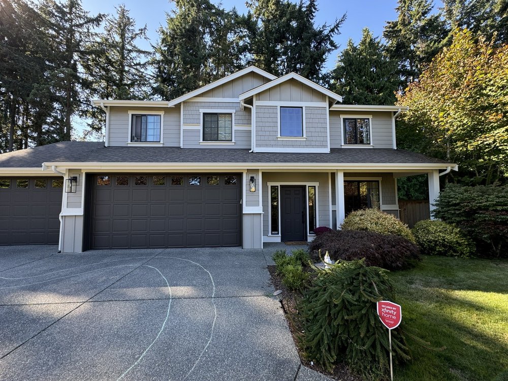Finished exterior repaint of a two-story Seattle home with warm gray siding, white trim and dark garage doors