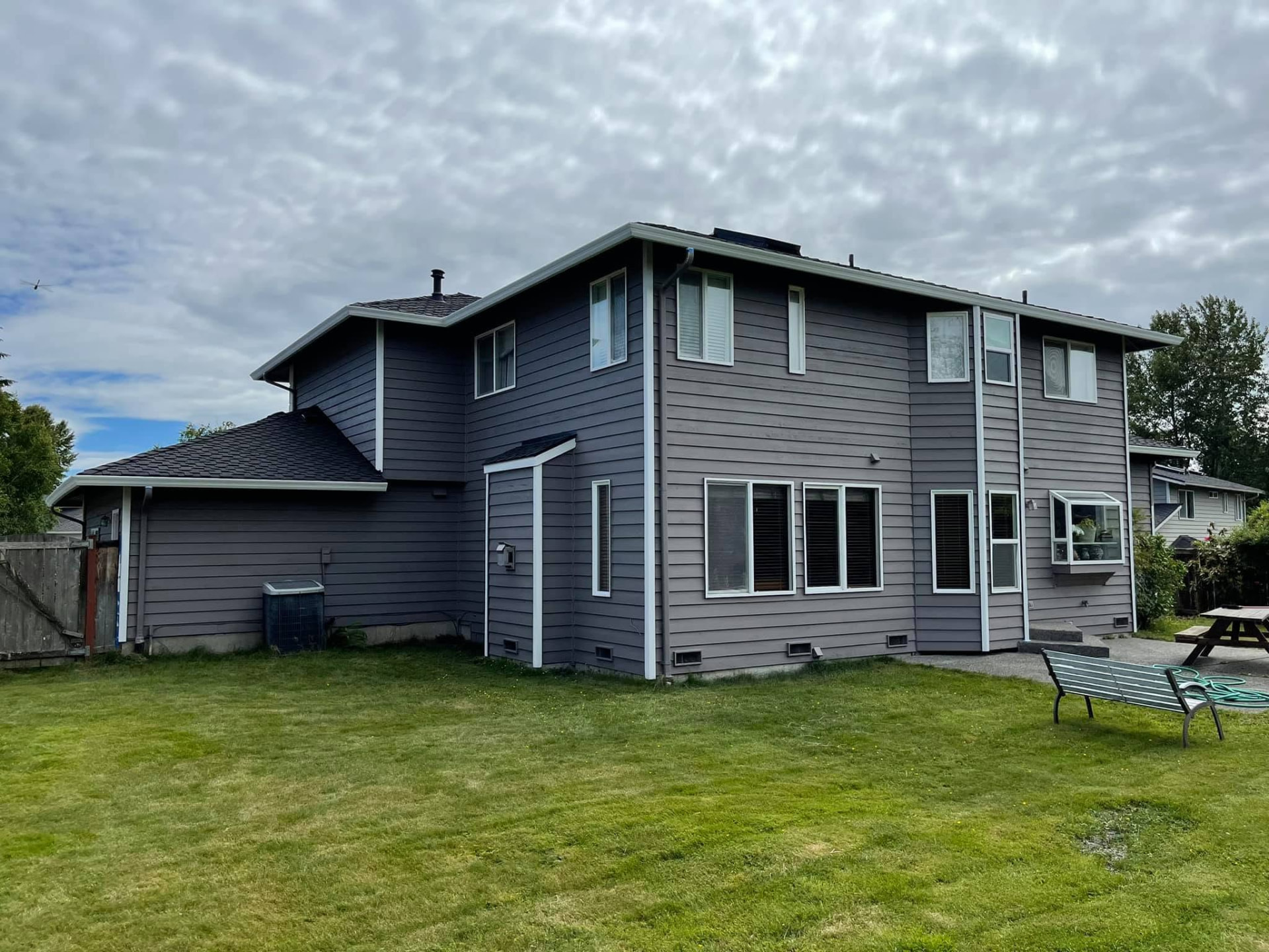 Rear elevation finished in deep slate gray lap siding with white trim, fascia and window casings