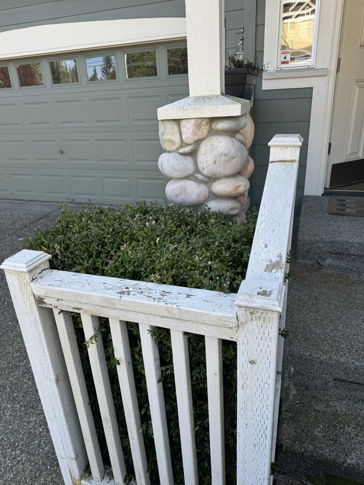 Chipped white front gate and railing beside a stone porch column before repainting