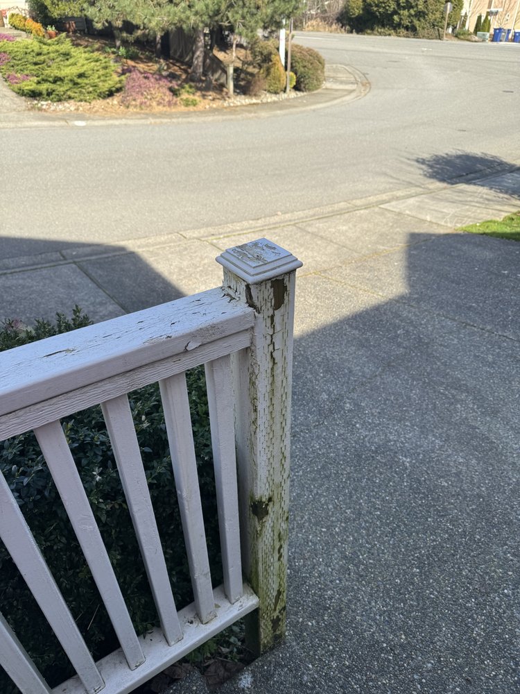 Close-up of a porch railing post with cracked, flaking white paint before prep