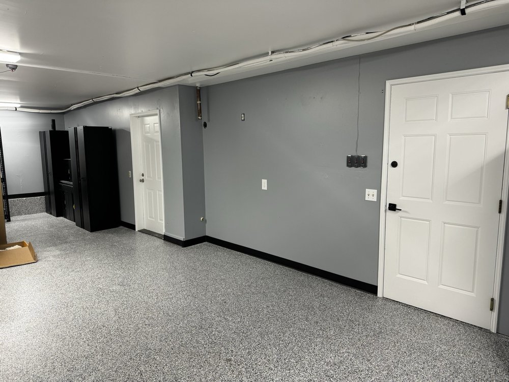 Finished garage interior with gray painted walls, black baseboards and white doors