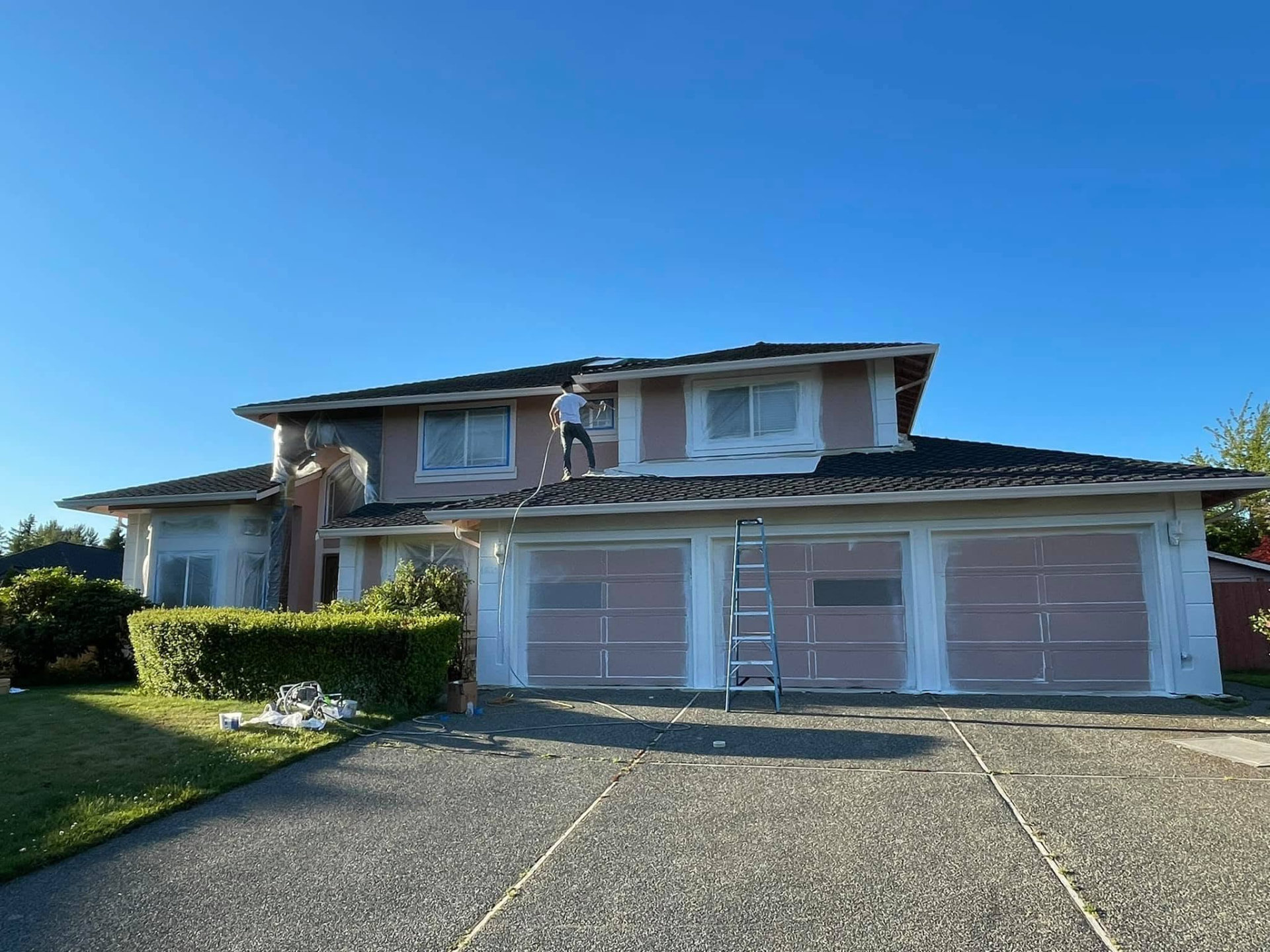 Front elevation of a two-story Everett home mid-project, siding and garage doors primed with windows masked off